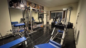 A gym with exercise equipment, mirrors, and blue benches. - Domus Hotel Veneza - Ipatinga (Ipatinga)