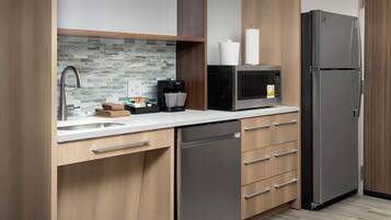 Una cocina moderna equipada con lavavajillas, un refrigerador de acero inoxidable, microondas y cafetera.