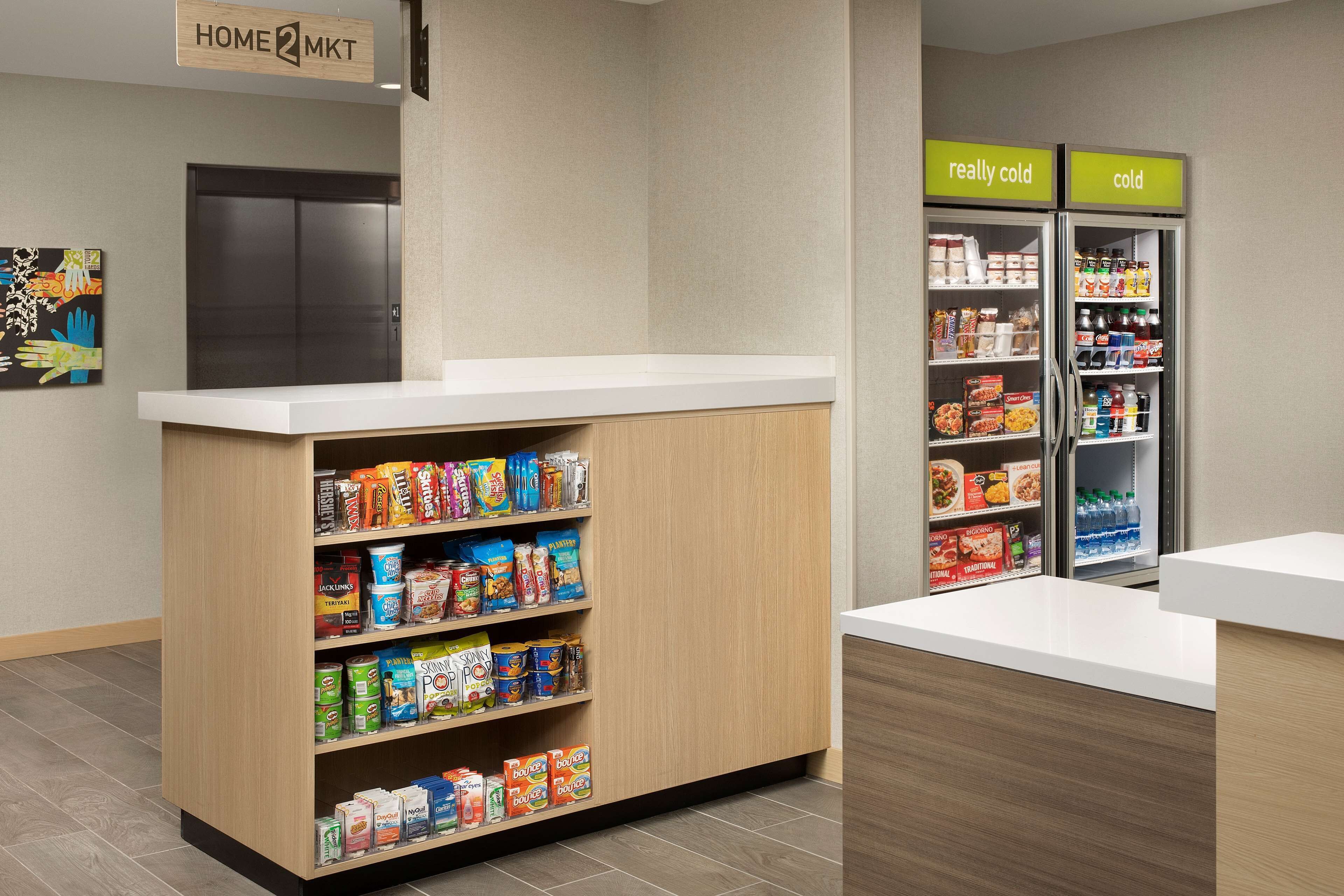 A reception area with a wooden counter, a refrigerator labeled "really cold" and "cold," and a sign for "HOME MKT."