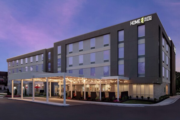 Un hôtel moderne doté d’une entrée couverte, de plusieurs étages et d’une enseigne indiquant qu’il fait partie de la chaîne Home 2 Suites by Hilton.