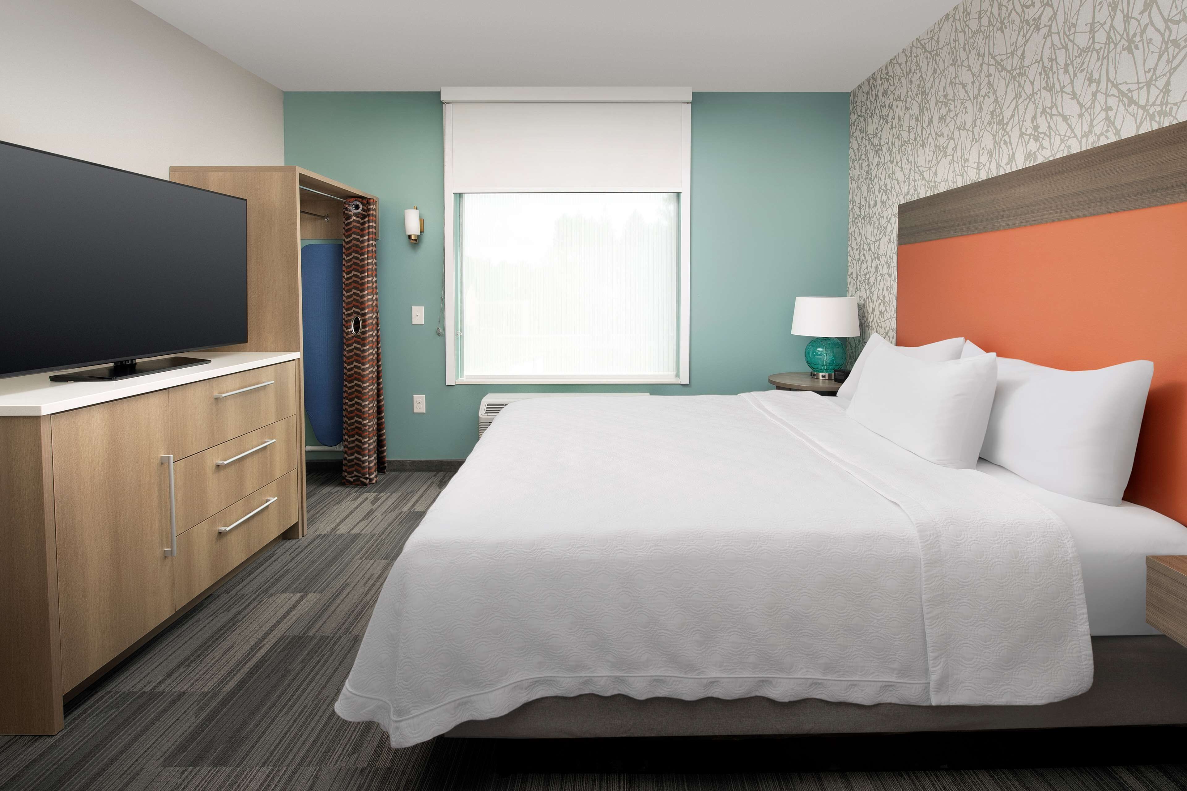 Ein Hotelzimmer mit Bett, Fernseher, Kleiderschrank und Fenster.