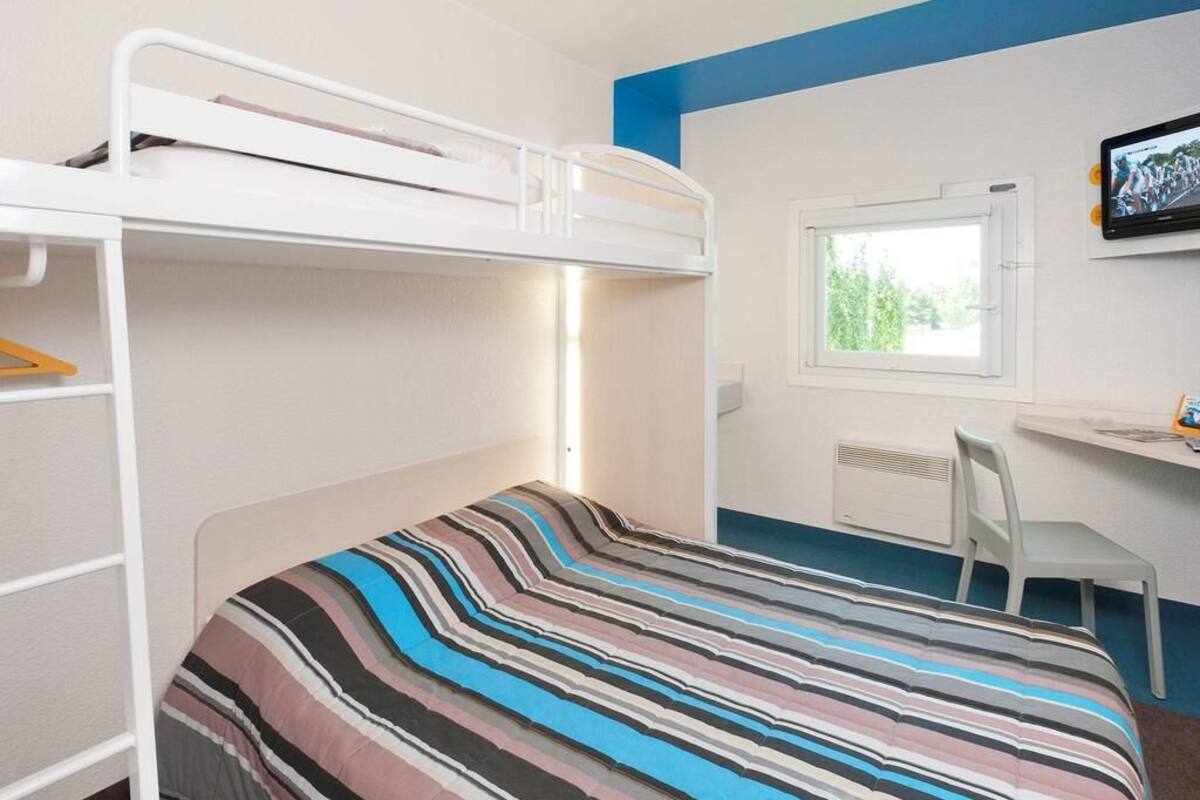 Habitación con literas, un escritorio, una silla, una ventana y un televisor.