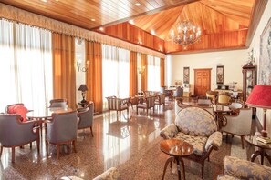 Un vestíbulo amplio con piso de madera pulida, un candelabro y diversas opciones de asientos, incluyendo sofás y sillones.