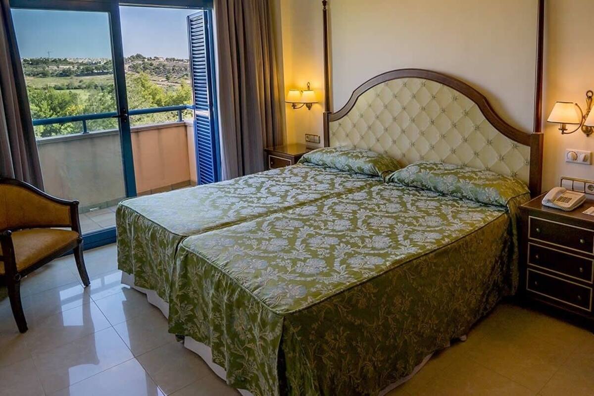 Une chambre d’hôtel comprenant un lit, deux tables de chevet, une chaise, un bureau et un balcon avec vue.