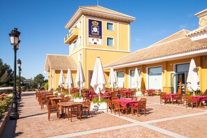 Un hotel con terraza, una torre del reloj y un cartel que indica un club de golf.
