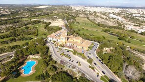 Vue aérienne d’un complexe hôtelier comprenant plusieurs bâtiments, une piscine et une végétation luxuriante.