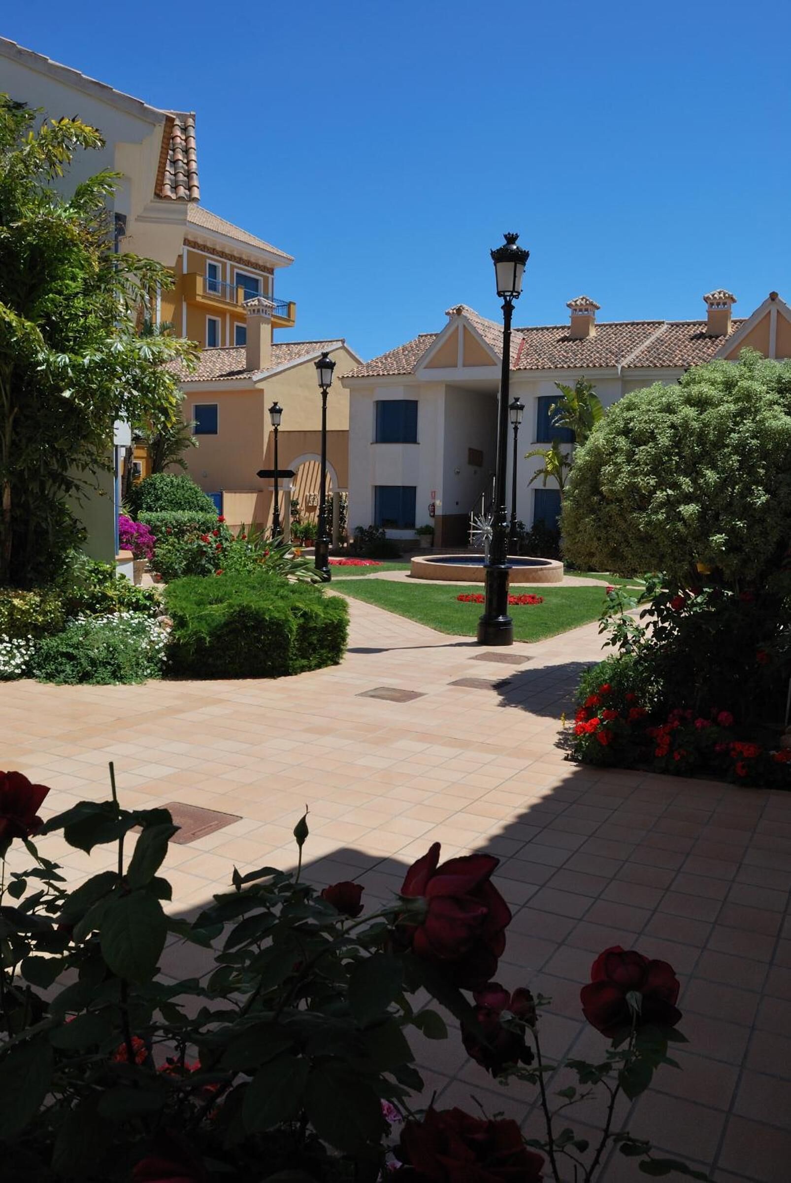 Un patio con un sendero, una fuente y un edificio de techo con tejas.