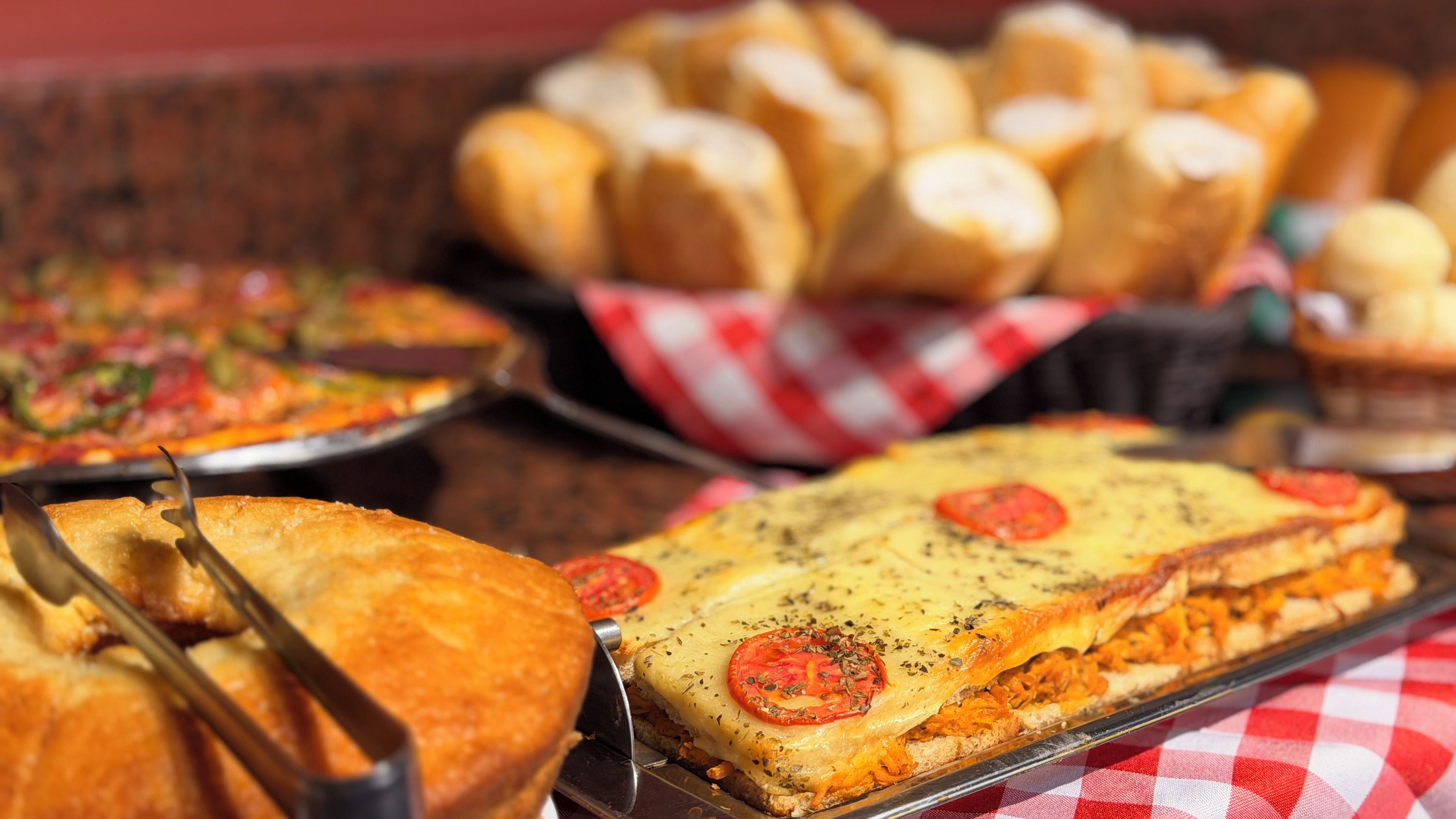 Diversos tipos de comida, incluindo pizza, pão e um prato com tomate e ervas.