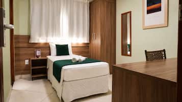 Una habitación de hotel con una cama, una mesita de noche, un escritorio y una silla.