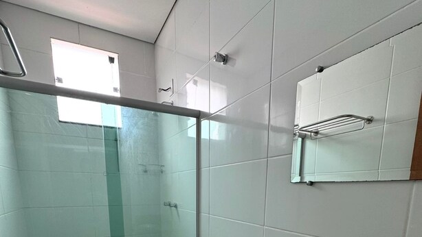 Un baño moderno con ducha de vidrio, inodoro blanco y lavamanos sobre encimera de granito.