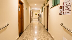 A hotel corridor with doors numbered 101 to 318, handrails on both sides, and a reception sign.