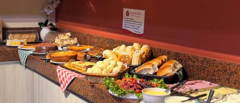A buffet with various food items including bread, pastries, and salads.