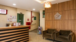 A hotel reception area with a wooden reception desk, a sign for the 'DOMUS HOTEL,' and a staircase leading to the upper floor. - Domus Hotel Cidade Nobre – Ipatinga (Ipatinga)