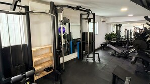 Un gimnasio con diversos equipos de ejercicio, como máquinas de pesas, bancos y una cinta de correr.