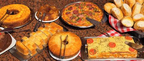 A variety of baked goods including pies, bread, and a layered dish on a granite countertop.