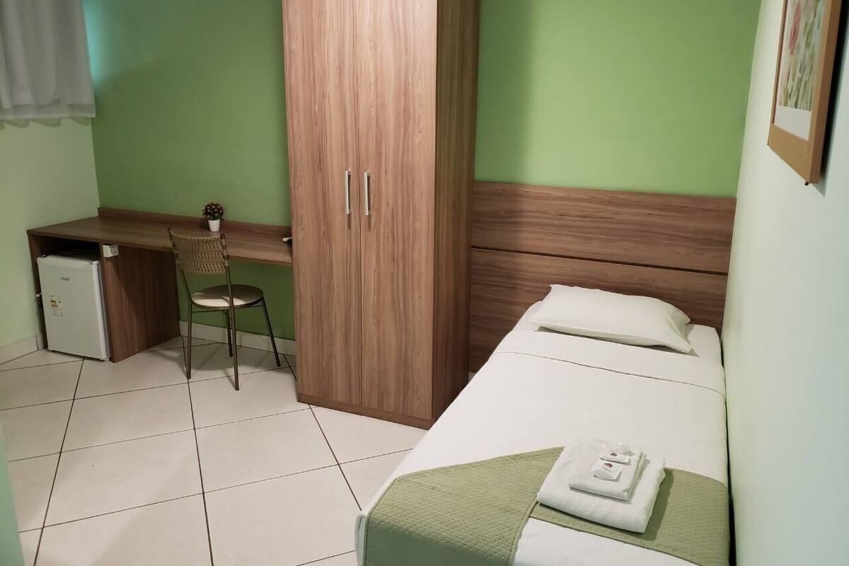 A room with a bed, a desk, a chair, and a wardrobe.
