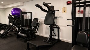 A gym with exercise equipment, a digital clock, and a purple exercise ball. - Domus Hotel Cidade Nobre – Ipatinga (Ipatinga)