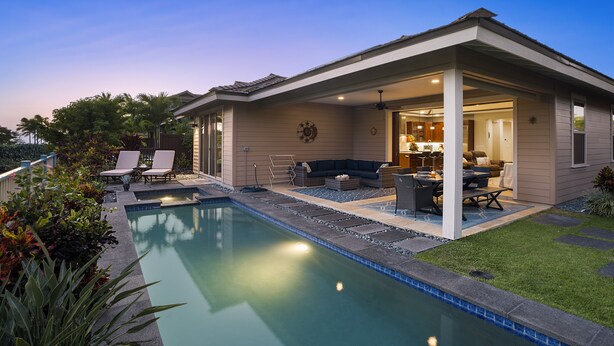 Una casa moderna con piscina, mobiliario exterior y un patio cubierto.