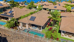 Un resort con varias casas, cada una con piscina y paneles solares en los tejados.