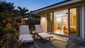 Una casa moderna con un patio que cuenta con dos sillones de descanso y una mesita con una copa y una botella de vino.