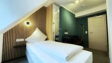 A modern hotel room with a bed, a desk, and a chair.