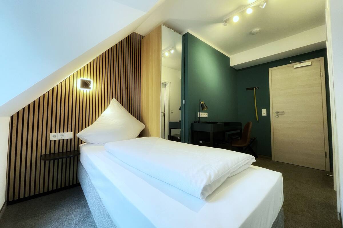 Ein modernes Hotelzimmer mit einem Bett, einem Schreibtisch, einem Stuhl und einer Tür.