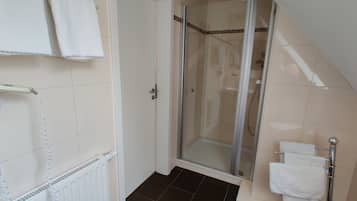 Een badkamer met een douche, een handdoekradiator en handdoeken op een rek.