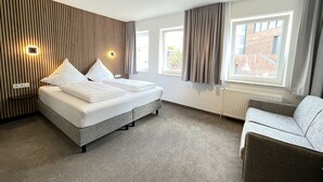 Una habitación de hotel moderna con una cama grande, un sofá y vistas a la ciudad.