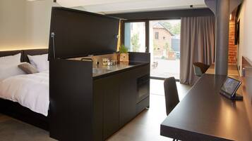 Una habitación de hotel compacta con cama, kitchenette y zona de comedor.