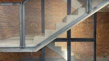 A staircase with metal railings and mesh panels, leading to a brick wall.