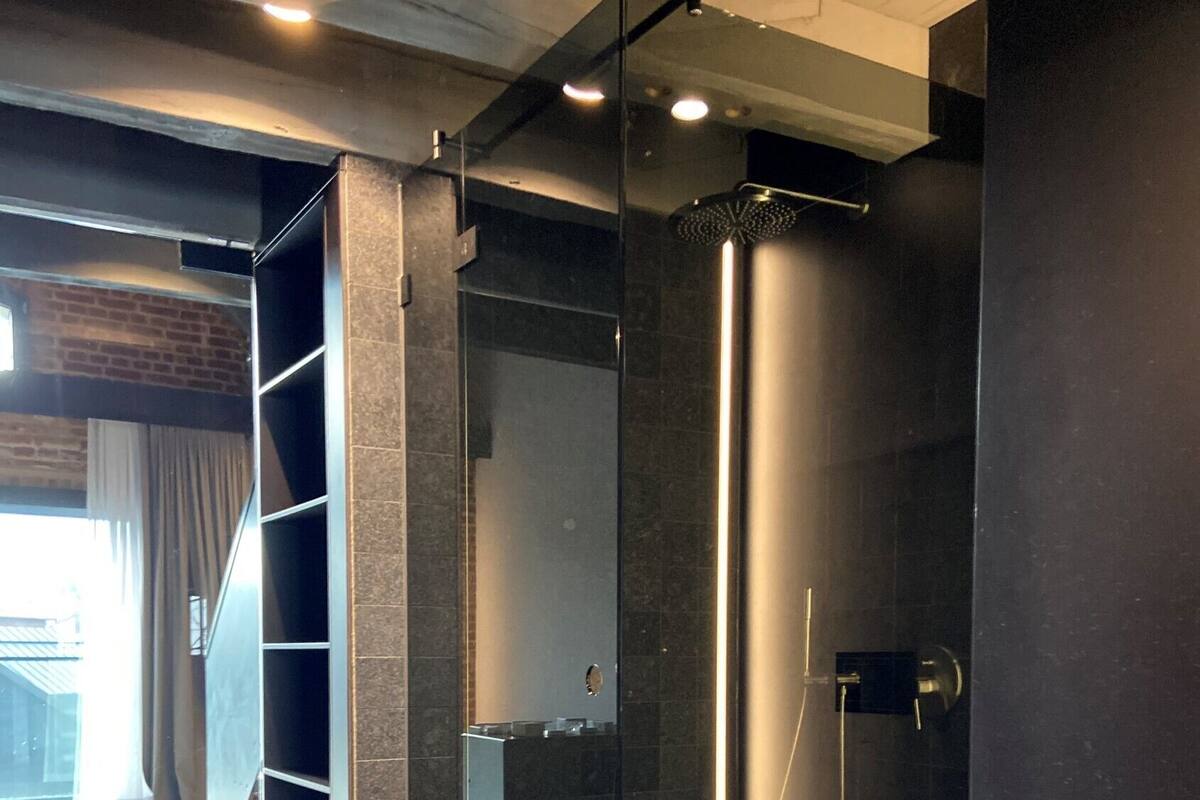 A modern bathroom with a glass-enclosed shower, a visible sink, and a tiled floor.