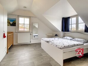 Cozy retreat with a large bed, window offering a view, and a minimalist design.
