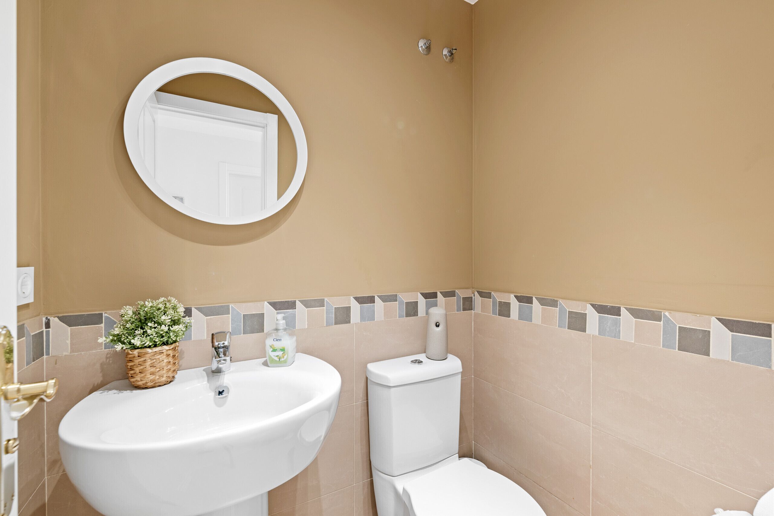Ein Badezimmer mit einem weißen Waschbecken, einer Toilette und einem Spiegel an der Wand.