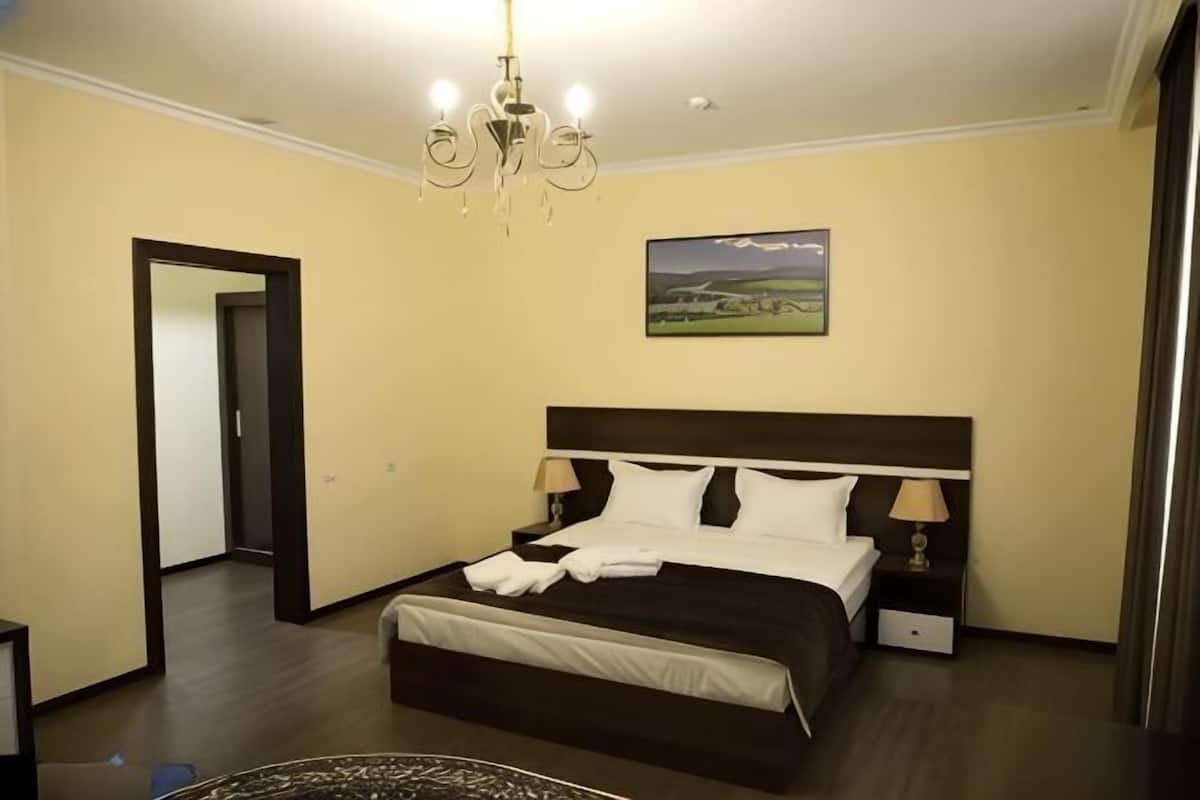 A bedroom with a bed, bedside tables, a chandelier, and a painting on the wall.