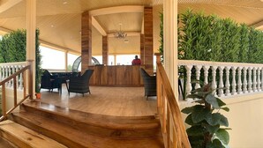 A wooden staircase leading to a reception area with a wooden desk and chairs, surrounded by greenery and a white balustrade. - Nimi Beach Resort (Freetown)