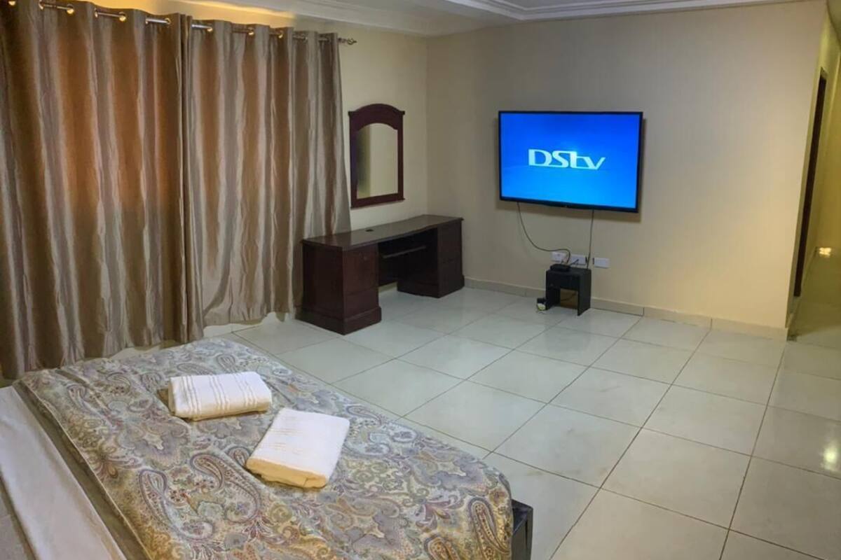 A hotel room with a bed, a TV, a dresser, and a mirror.