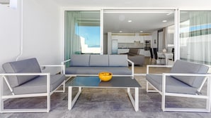 A modern living area with a sofa, two armchairs, a glass coffee table, and a yellow bowl.
