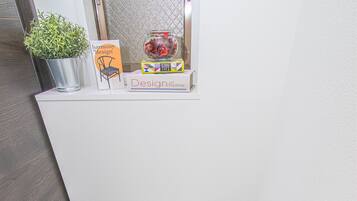 A modern bathroom with a white toilet, a potted plant, a Harmony Design book, and a decorative jar.