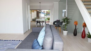 Un salon moderne avec un canapé gris, un tapis à rayures et un escalier menant à un niveau supérieur.