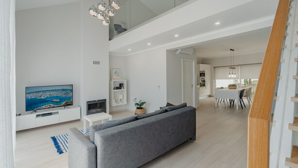 Un salon moderne avec un canapé gris, un téléviseur à écran plat et une cheminée.