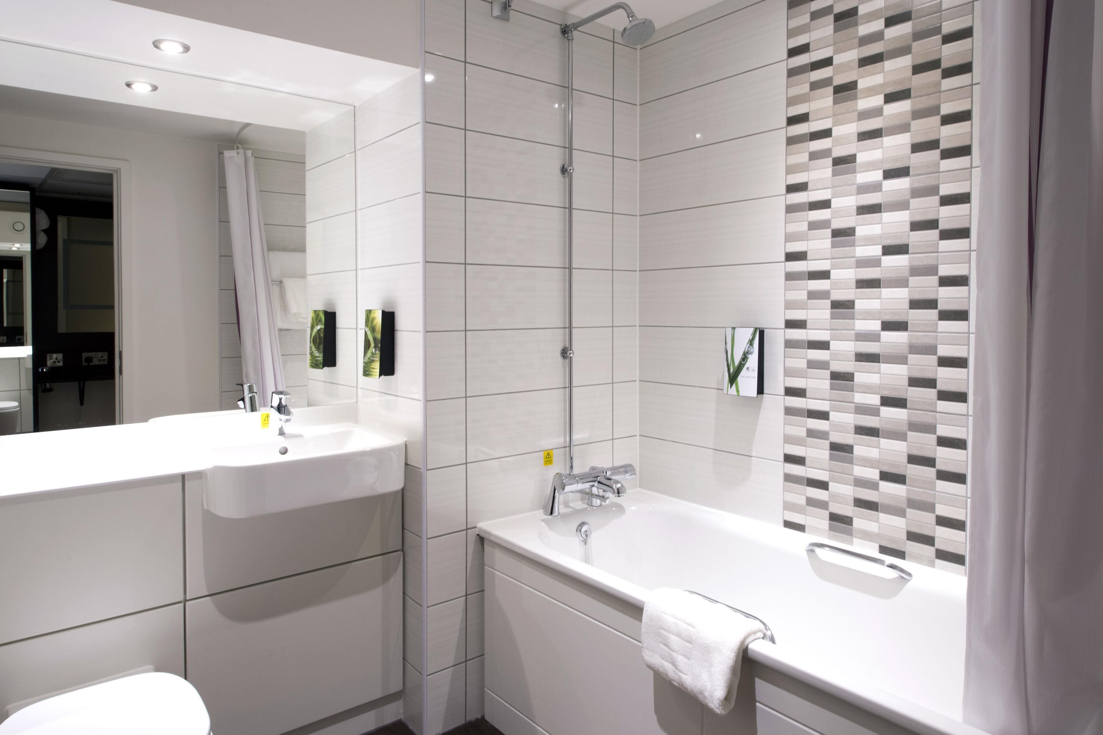 Une salle de bain moderne avec un grand miroir, deux lavabos, une baignoire et une douche.