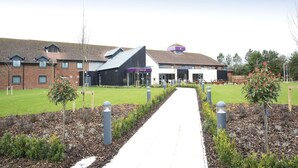 A pathway leading to a building with a modern design, surrounded by landscaped areas and bollards. - Premier Inn Newbury Town Centre South A339 (Newbury)