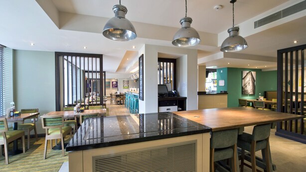 A modern hotel lobby with a central island, seating areas, and a bar. - Premier Inn Newbury Town Centre South A339 (Newbury)