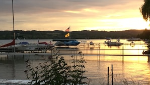 Un port de plaisance avec des bateaux amarrés, un drapeau et un coucher de soleil paisible sur l’eau.