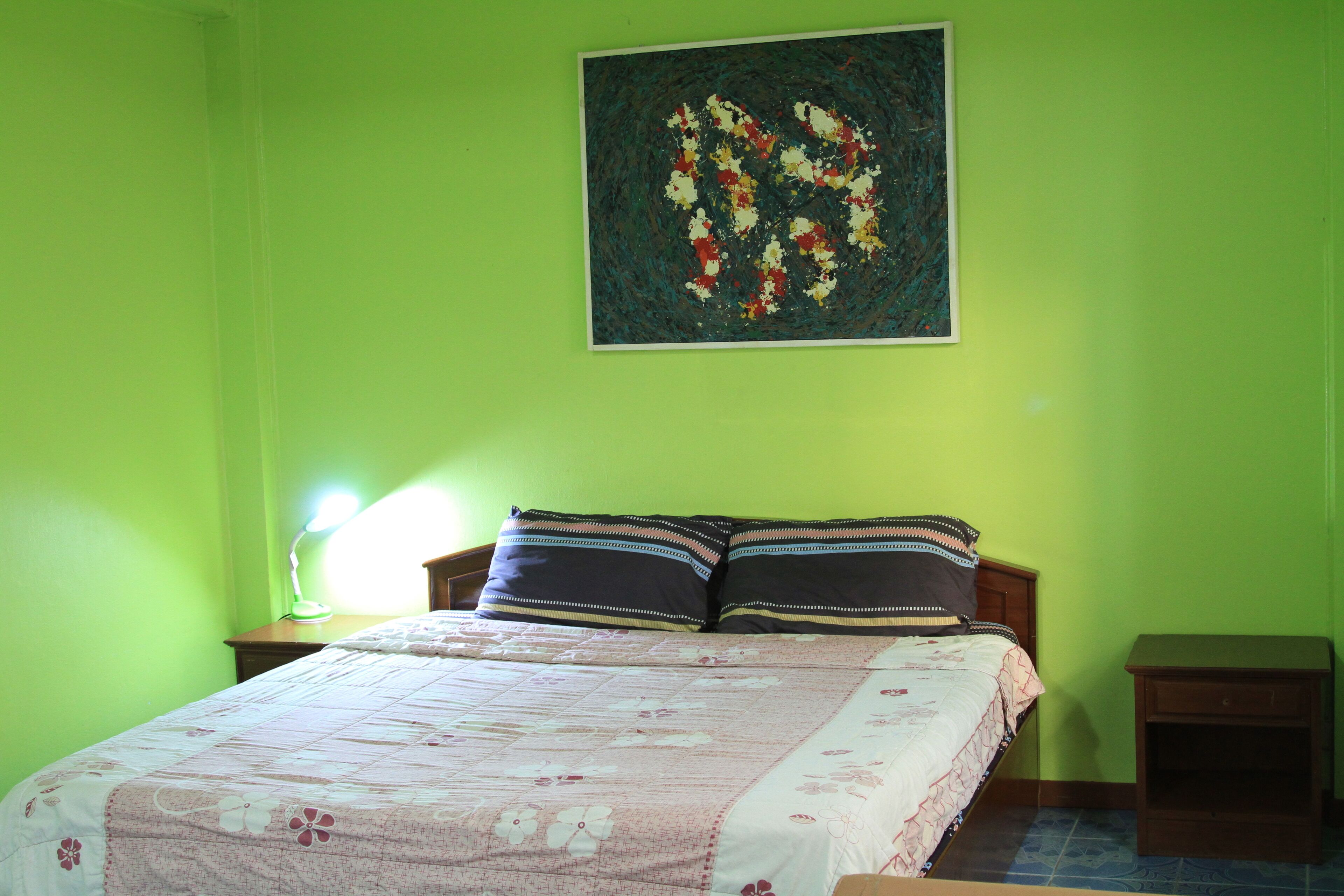 A bedroom with a bed, two nightstands, a lamp, and a painting on the wall.