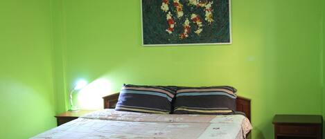A bedroom with a bed, two nightstands, a lamp, and a painting on the wall.