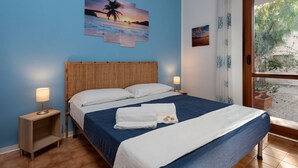 Ein Schlafzimmer mit einem Bett, zwei Nachttischen, einer Wand mit drei Bildern und einem Fenster mit Vorhängen.