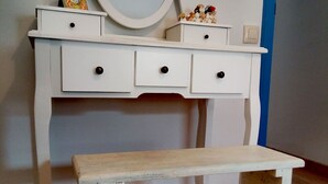 A white dresser with a round mirror and three drawers, a small shelf with decorative items, and a wooden bench in front. - Casas del Castillo de Peñíscola EGVT-498-CS - Deluxe Apartment (Peñíscola)