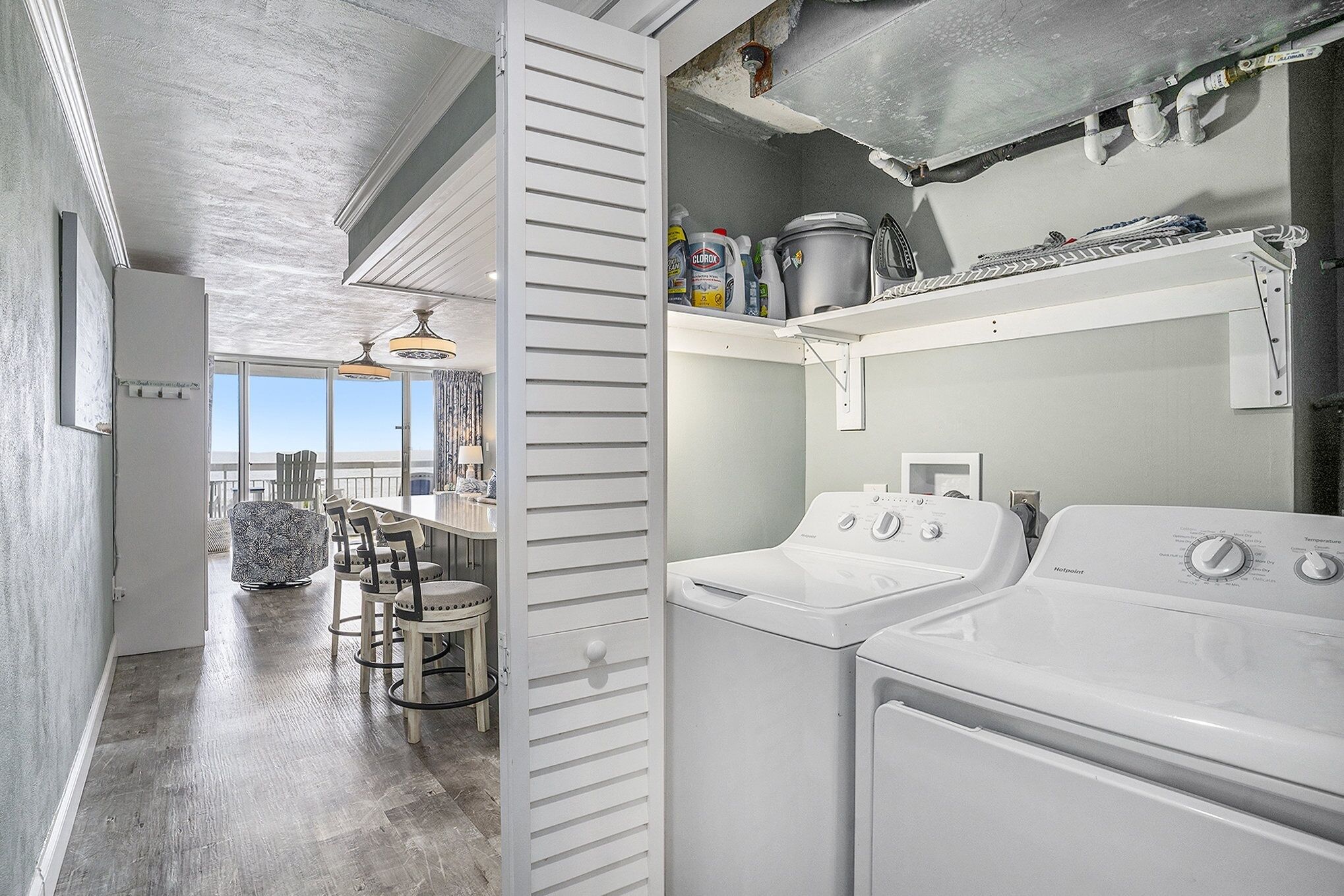 A laundry area with two washing machines, a drying rack, and various cleaning supplies.