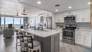 A modern kitchen with white cabinets, stainless steel appliances, and a large island with bar stools. - 0209 Waters Edge Resort 1 Bedroom Condo by RedAwning (Murrells Inlet)